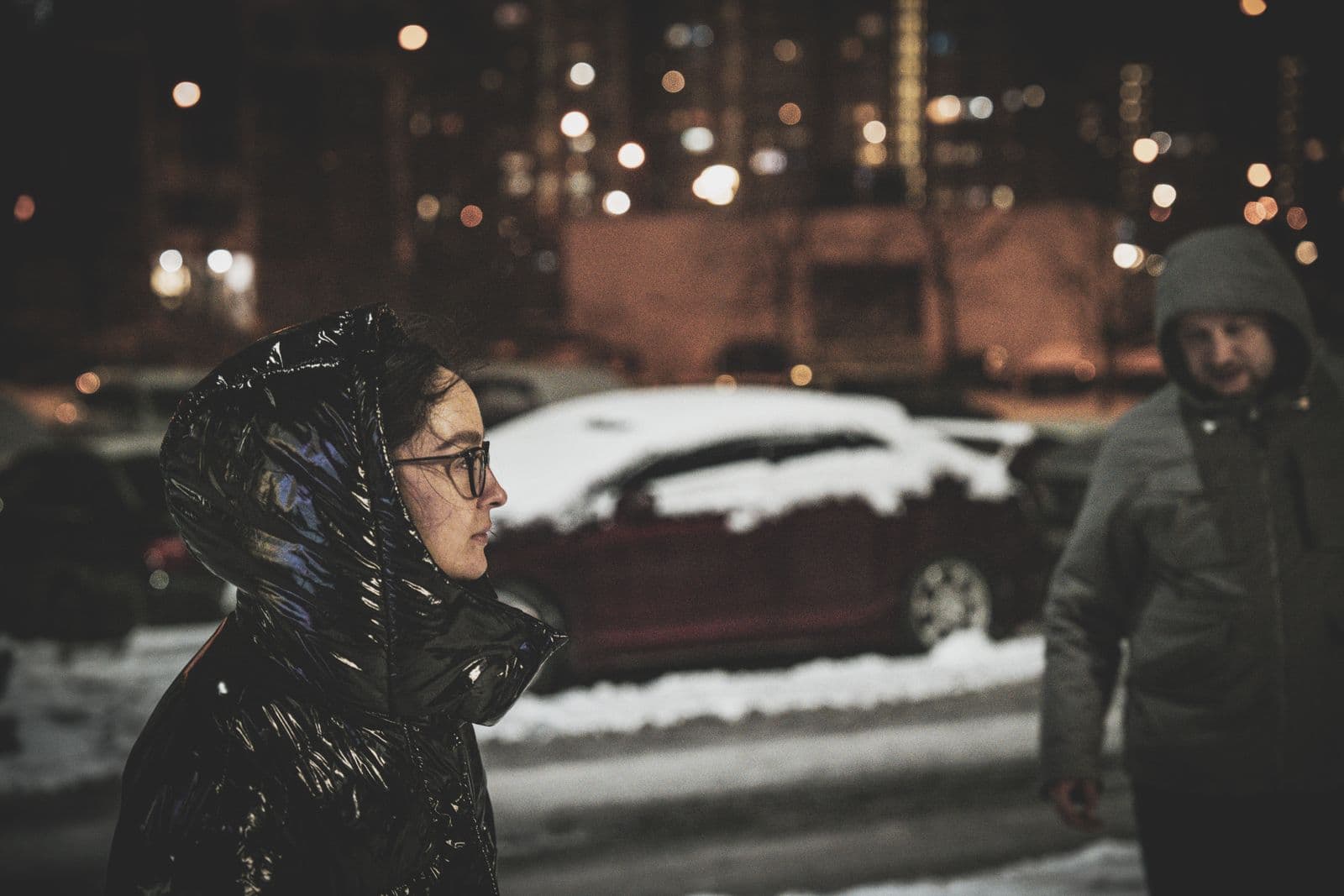 People in long padded coats walking down a snowy street in Seoul