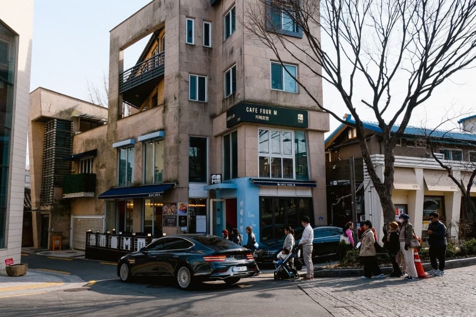 카페가 있는 건물 앞 도로에 승용차와 유모차를 동반한 보행자들이 보인다.